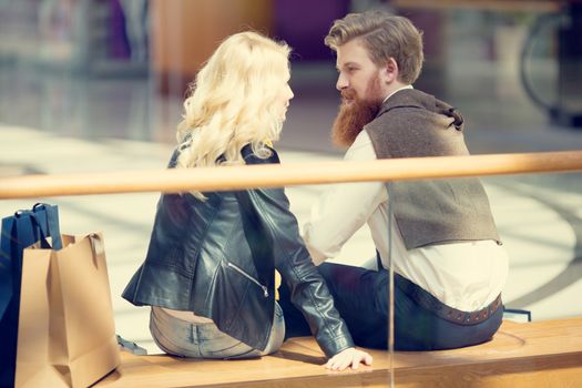 Happy beautiful young couple with shopping bags in mall