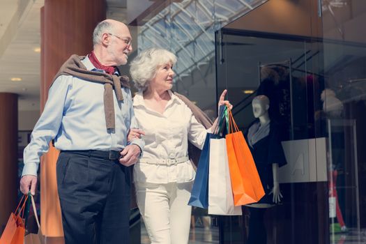 Adult senior couple with purchases in bags at shopping mall