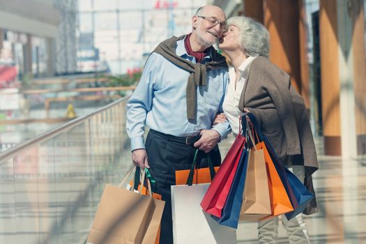 Adult senior couple with purchases in bags at shopping mall