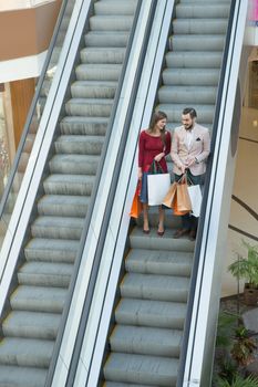 Happy beautiful young couple with shopping bags in mall