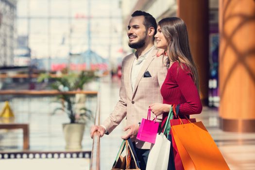 Happy beautiful young couple with shopping bags in mall