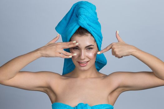 Beautiful woman with towel on head applying creme after shower