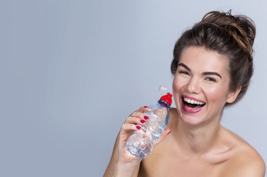 Portrait of a beautiful happy woman with perfect skin holding bottle of water