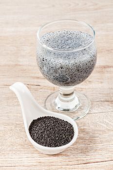 Lemon basil seeds in white spoon and soak in water on wooden background.