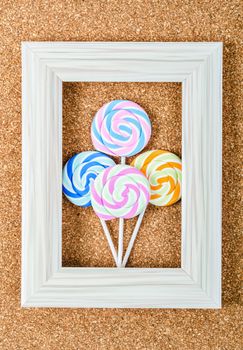 Colorful lollipop in vintage frame on wooden background.