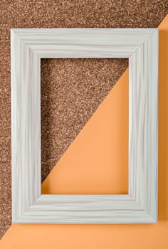 Empty white vintage frame on orange color and wooden flat lay.