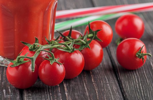 Cherry tomatoes and glass of tomato juice in the background. Tubules for a cocktail. Blurred background.