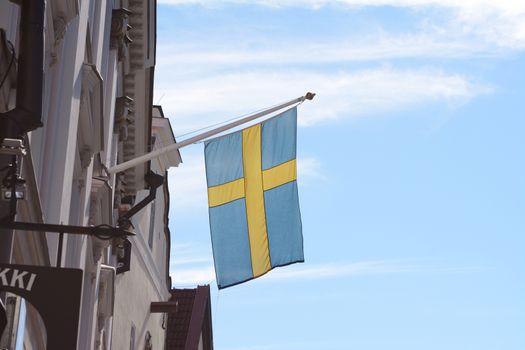 The Swedish flag flies from a building against a blue sky in Tallinn, Estonia