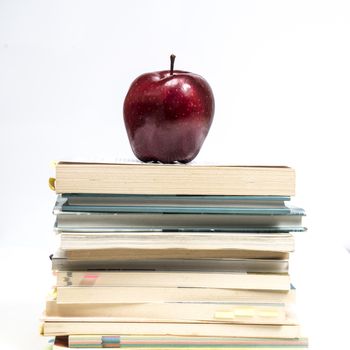 a red apple on top of a pile of books