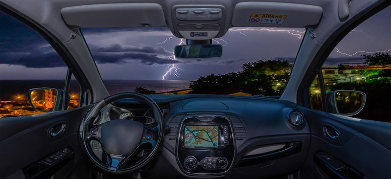 Looking through a car windshield with view over lightning storm over the sea