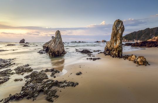 Early morning light shines forth across the ocean and onto the rocky shores of the beach.  South Coast Australia