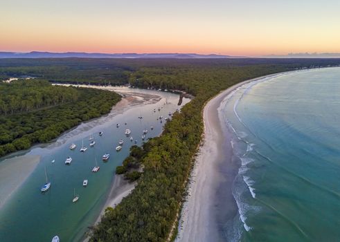 Scenic coastal landscape beautiful beach and inlet with moored yachts and boats.  Morning sky at dawn with soft light.  Australia