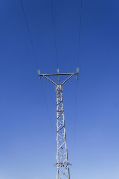 High voltage tower with three cables and blue sky as background