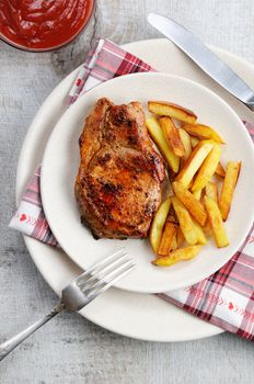 Juicy, browned pork steak on a bone with fried potatoes