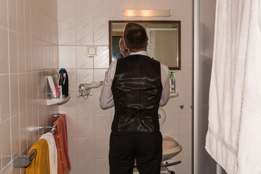 Young man in the bathroom in front of the mirror while shaving.