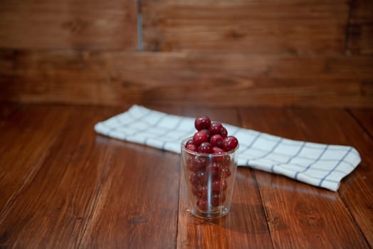 Sweet cherry, black cherries in a glass on wooden background.