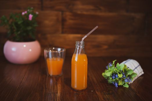 Fresh juice in bottle on wooden table with flowers
