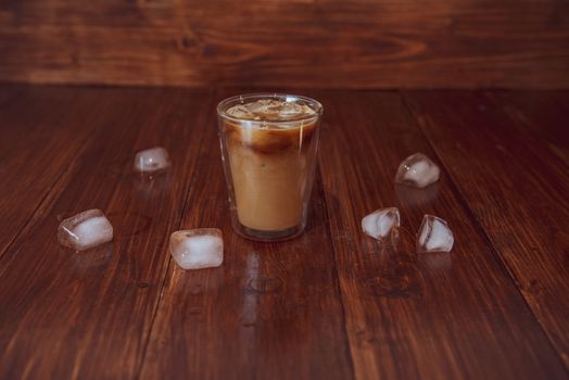 Iced coffee with ice cubes on table.