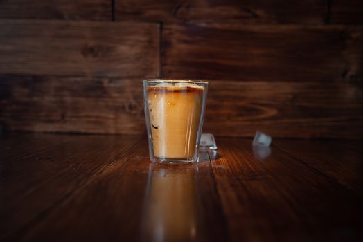 Iced coffee with ice cubes on table.