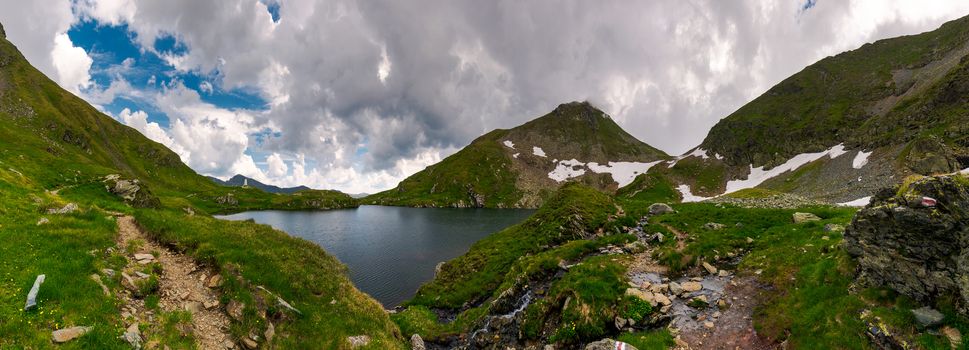 panorama of Capra lake, Romania. gorgeous landscape of Fagarasan mountains on a cloudy summer day