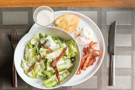 Caesar salad served with crispy bacon and poach egg