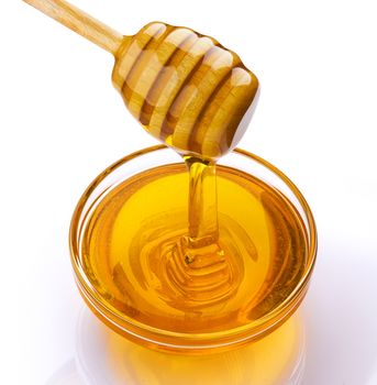 Honey stick and bowl of pouring honey isolated on white background with clipping path