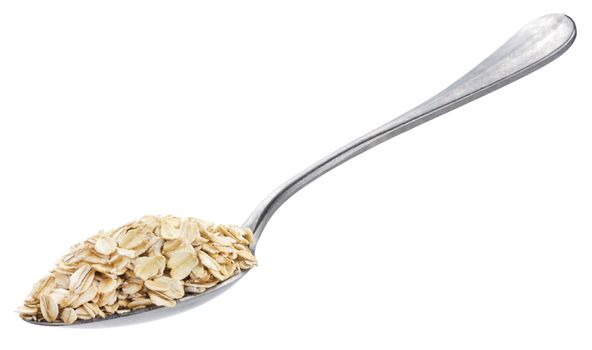 Oat flakes in spoon isolated on white background with clipping path