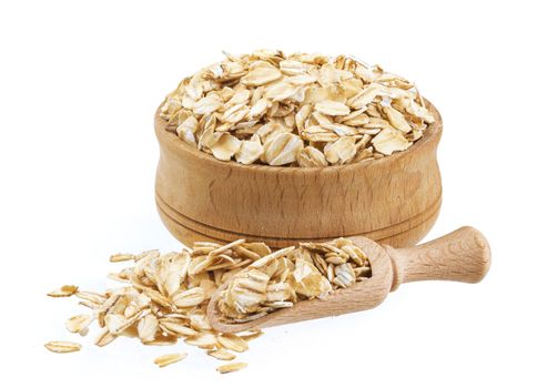 Isolated oatmeal. Oat flakes in wooden bowl on white background