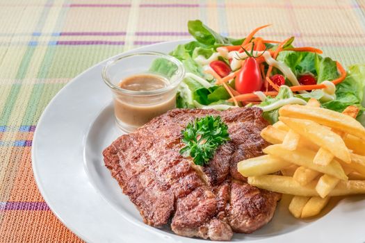 Grilled steak with french fries and fresh vegetables on white plate
