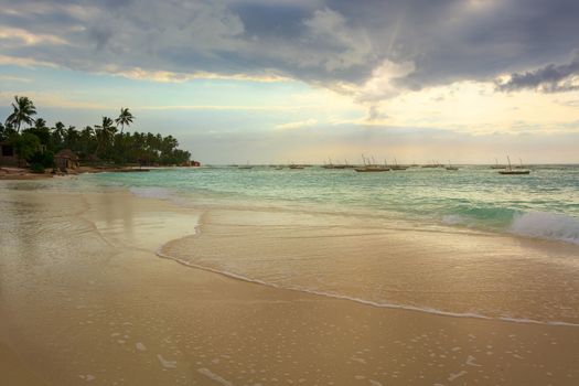 A nice beach with Several fishing boats  anchored at sunset with sunbeams.Zanzibar coast,Tanzania.