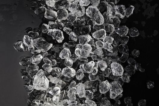 Pieces of crushed ice cubes on black background. Copy space, top view