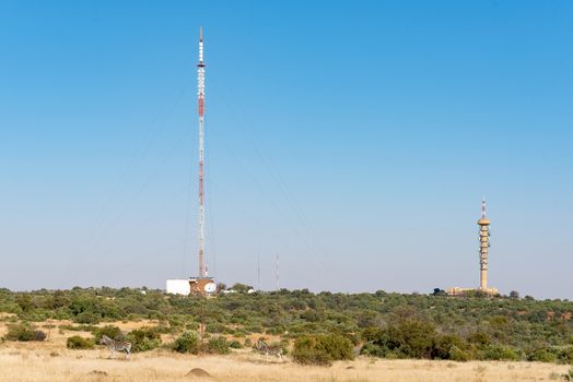 A microwave telecommunications tower and a TV and radio broadcast tower on Naval Hill in Bloemfontein. Two zebras are visible in front