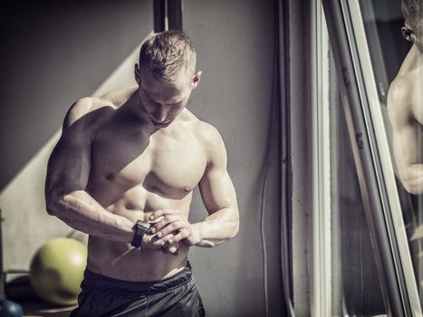Young attractive man in gym checking sports watch to track his workout, heart pulse or fitness