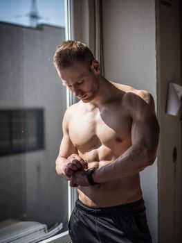 Young attractive man in gym checking sports watch to track his workout, heart pulse or fitness