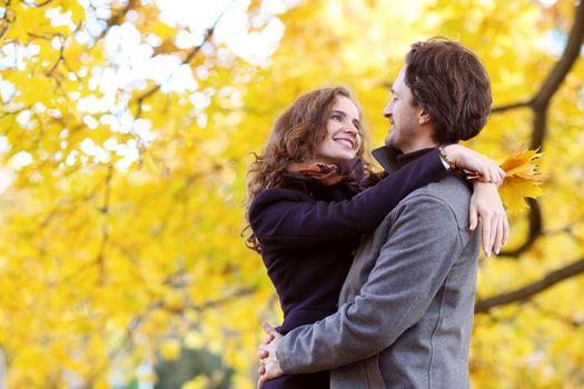 Love, relationship, family and people concept - smiling couple hugging in autumn park