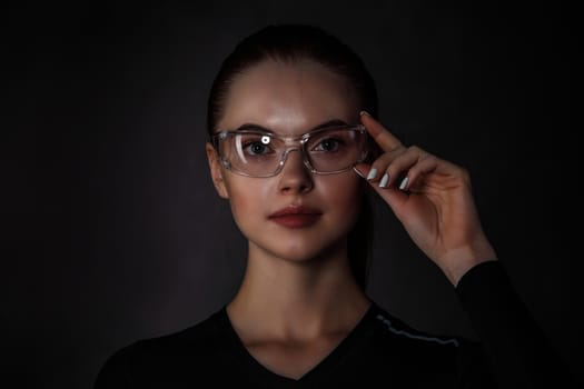 Beautiful woman with transparent futuristic glasses on dark background