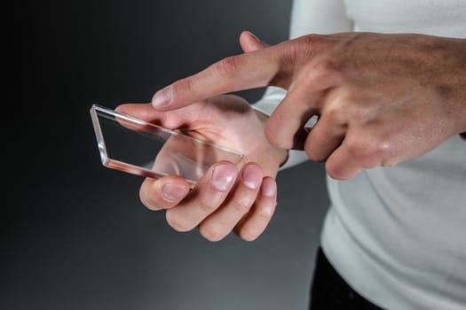 Male hands holding blank futuristic transparent mobile, smart phone with copy space