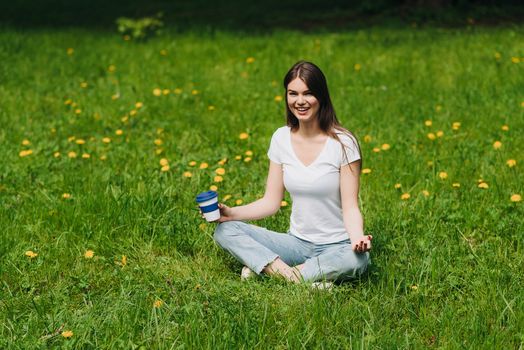 Beautiful young woman enjoy nature sitting in park with coffee