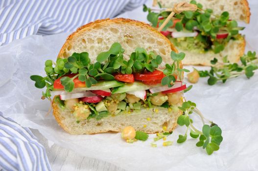 Sandwich with green radish sprouts crispy radish and cucumber, tomato with avocado dressing and mustard with herbs.