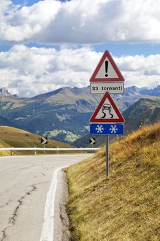 Warning road sign on a mountain road in Dolomites, Italy