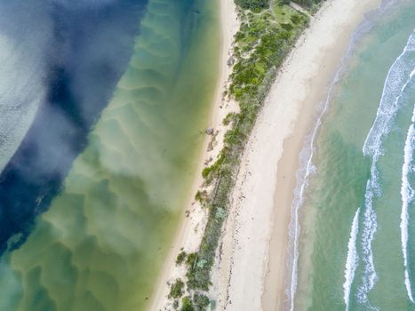 Where ocean meets river, separated by a narrow sand dune.  Aerial views  showing snd wave patterns and colours.