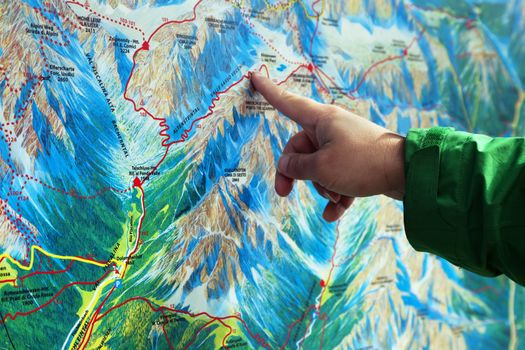 Finger pointing on a trekking map of an area in Dolomites, Northern Italy