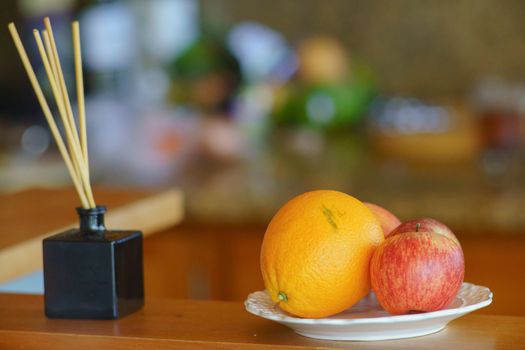 Fruit on the bar. Juicy bright orange and apples. A small vase with aromatic chopsticks. A healthy home atmosphere. Abstract home light bokeh defocused background