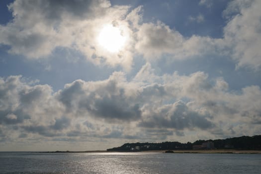 Bright and high summer sky. The sun makes its way through the clouds. Like a glass surface of water. Backlit image.