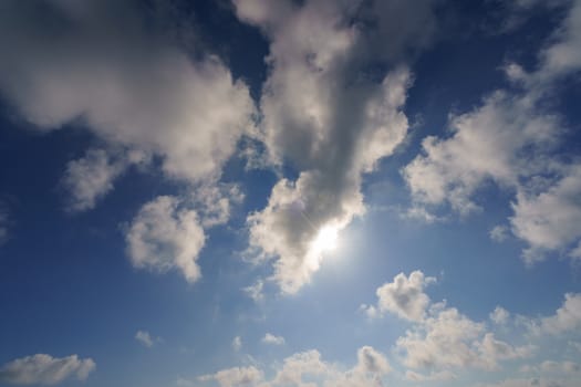 Bright and high summer sky. The sun makes its way through the clouds. Backlit image. Backlit image