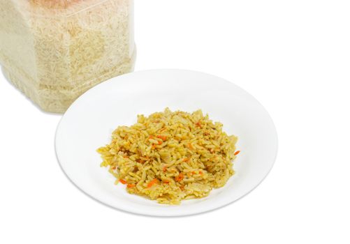 White dish with rice cooked with carrots and spices against of a fragment of the transparent plastic container with uncooked rice on a light background
