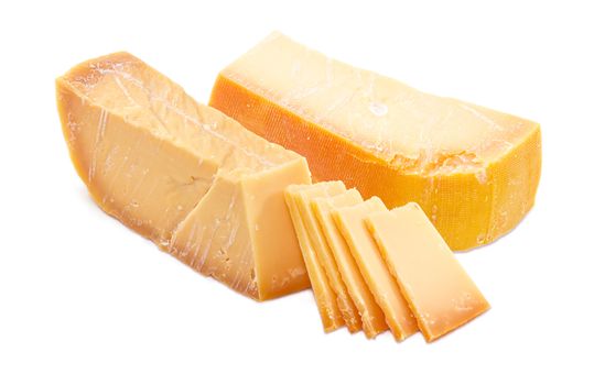 Two pieces and several slices of the Dutch hard cheese Beemster closeup on a white background
