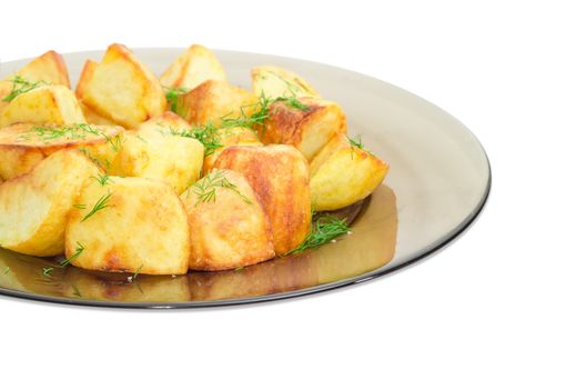 Fragment of the dark glass dish with serving of the country style fried potatoes sprinkled by chopped dill closeup on a light background
