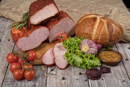 Ham, bread and vegetables on a wooden desk