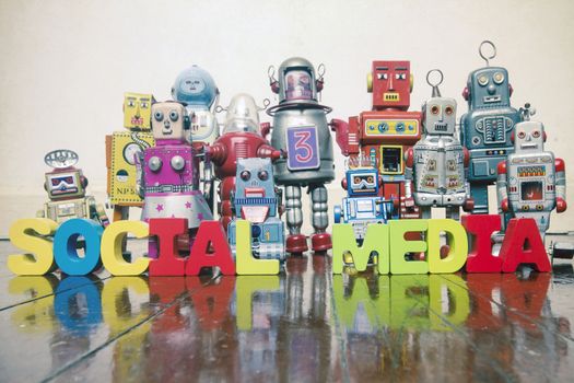the words SOCIAL MEDIA   with rtro robot toys on a wooden floor with reflection